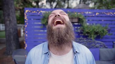 Neşeli sakallı mutlu adam kameraya bakıyor ve komik şakalara gülüyor. Geniş tebessümlü kel adam eğleniyor. Mizahın tadını çıkarıyor.