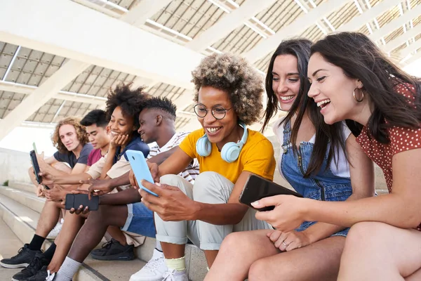 Grupo de jovens mestiços com telefones celulares. Alunos entusiasmados usando seus dispositivos tecnológicos. Conceito de jovem empreendedor, amigável, selfie, app, hipster, millennial. — Fotografia de Stock