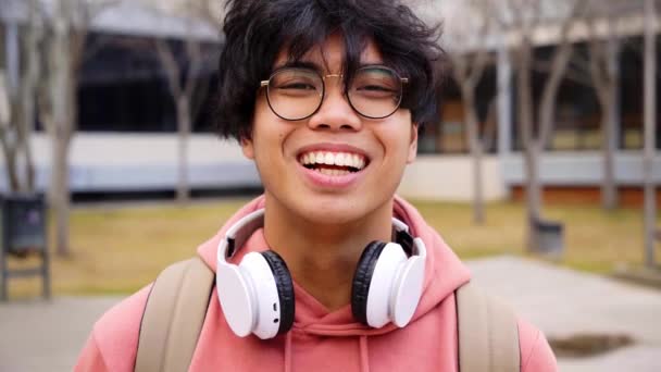 Close up tiro de alegre feliz asiático adolescente menino olhando para câmera sorrindo. Olhar intenso de um jovem. — Vídeo de Stock