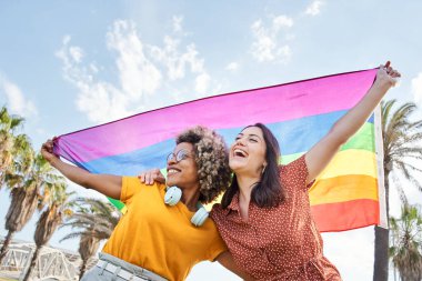 Genç lezbiyen çift gurur gününü gökkuşağı bayrağıyla kutluyor. Homoseksüellik kavramı, gay.