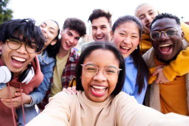 Bir grup neşeli genç arkadaş selfie portresi çekiyorlar. Mutlu öğrenciler kameraya bakıp gülümsüyor. Toplum kavramı, meslektaş, gençlik yaşam tarzı ve arkadaşlık