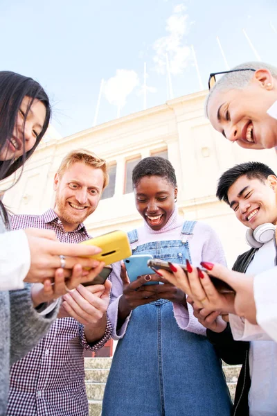Vertical photo of Group of multirracial friends using mobile cell together outdoors having fun watching smart phone. Diversity People Meeting Relaxing Connection Communication Community Concept. — Stock Photo, Image