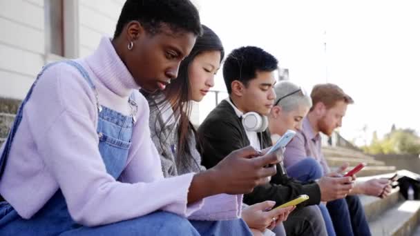 Group of multirracial friends using mobile cell together outdoors watching smart phone with serious face. Diversity People Meeting Relaxing Connection Communication Community Concept. — Stockvideo