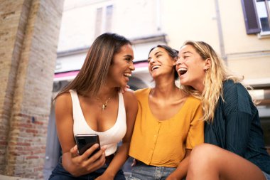 Dışarıda cep telefonu kullanan üç çok ırklı kadın. Gençlik ve sosyal medya ağı. 