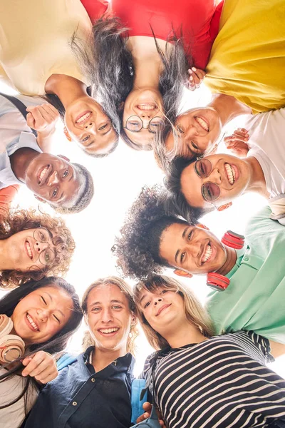 Low angle of a group of students are together, happy and smiling. Faces of young teenagers looking at camera, hugging. Vertical photo. — Foto de Stock