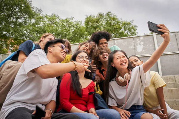 Group of multi-ethnic students taking selfies with mobile phone. Teenagers using a smart phone and having fun together. — Stock Fotó