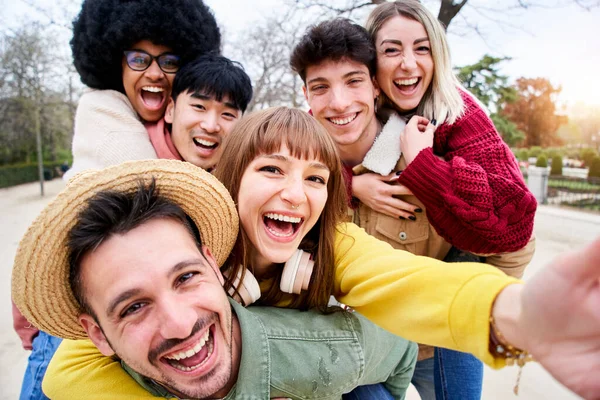 Cheerful group of happy friends taking smiling selfie in piggyback. Three couple having fun together outdoors at park in the city. People enjoying travel in vacation holidays. — Foto de Stock