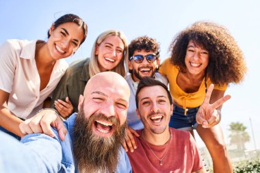 Neşeli bir grup kız ve erkek selfie için poz veriyor ve eğleniyorlar. Arkadaşlık ve toplum kavramı