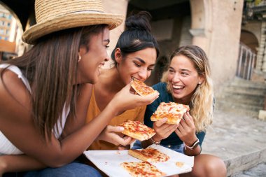 Şehirde pizza yiyen üç kızdan oluşan komik bir grup. Genç bayan turist yaz tatillerinde eğleniyor. Yüksek kalite fotoğraf