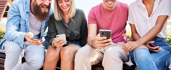 Çok ırklı mutlu arkadaş grubu dışarıda telefonla gülüşüyor. Teknolojiye ve sosyal medyaya bağımlı insanlar. Yüksek kalite fotoğraf