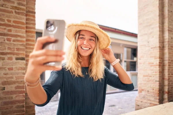 帽子をかぶって笑顔の自撮りを取る夏服の美しい幸せな女性 携帯電話を使用して女性ブロンド ソーシャルメディアです 高品質の写真 — ストック写真