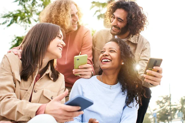 Happy friends using mobile and laughing. Smiling people holding smart phones. Youth culture and technology online concept. High quality photo