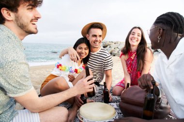 İnsanlar yaz tatili partisini kutluyorlar. Beş güzel arkadaş, deniz kenarında bira içip, eğleniyor, gülüyor ve eğleniyorlar. Yüksek kalite fotoğraf