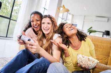 Bir grup genç bayan çok ırklı genç arkadaş evde video oyunları oynuyorlar. Sadece kadınlar oynar ve patlamış mısır yer. - Evet. Yüksek kalite fotoğraf