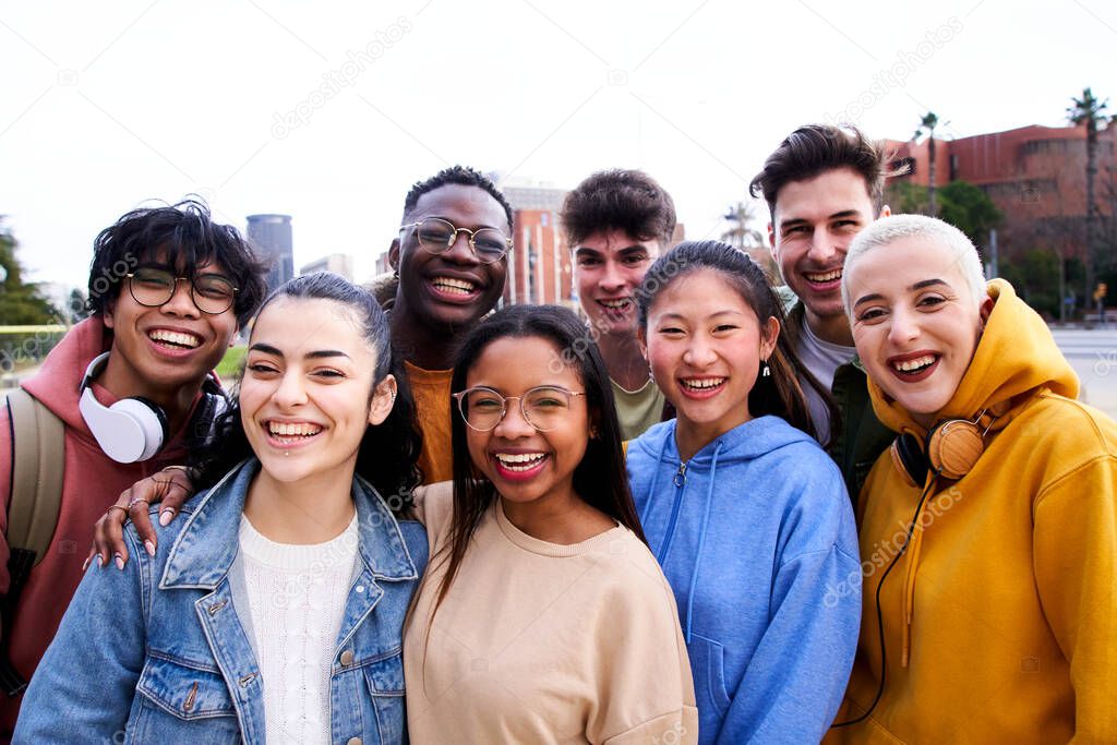 Confident multiracial group of students holding books and smiling at camera, campus university on background, learning and education concept. Smiling happy people having fun together. International