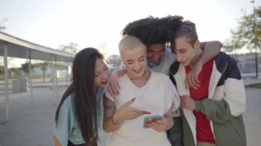 Group of happy friends using phone and having fun in the street. Teenagers sharing with mobile cell in video call. High quality photo