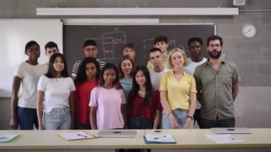 Portrait of a group of students hugging each other in class looking at the camera. Young people of different ethnicities posing for a photo in the classroom. Back to school. High quality 4k footage