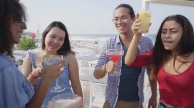 Slow motion Friends at summer party cheers dance and having fun drink color cocktails in a rooftop bar. We are so lucky to have each other. High quality FullHD footage