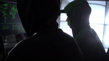 Criminal team Hacker using computer for organizing massive data breach attack on government and big company servers. Dark room surrounded computers. High quality 4k footage