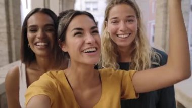 Three happy young woman girlfriends in summer clothes talk in video call selfie streaming online outdoors at the touristic place of Florence. High quality 4k footage