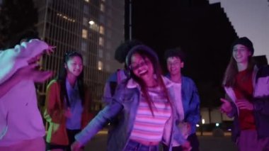 Şehirdeki bir sokak partisinde dans eden bir grup modaya uygun genç. Arkadaşların eğlence ve gençlik kültürü kavramı. Yüksek kalite 4k görüntü