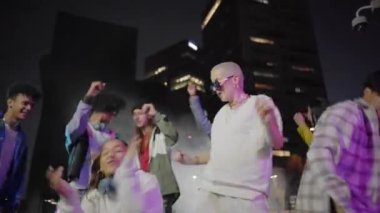 Kentteki parti gecesinde dans eden gençler. Modern çok kültürlü arkadaşlar birlikte müzikten zevk alıyorlar. Yüksek kalite fotoğraf