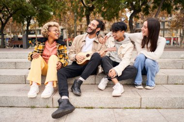 Mutlu arkadaşlar şehirde ukulele çalıp şarkı söylüyorlar. Yüksek kalite fotoğraf