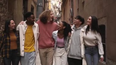 Bir grup mutlu genç arkadaş şehrin sokaklarında yürüyor. Gülümseyen öğrenciler birlikte gülüyor ve eğleniyorlar. Yüksek kalite fotoğraf