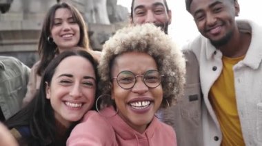 Genç çok ırklı insanlar akıllı telefonlarıyla selfie çekiyor ve açık havada eğleniyorlar. Yüksek kalite fotoğraf