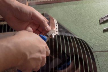 Kargaburnlu usta, kabloları bağlamak için penseyi ısıtmalı bir film zemininde bakır şeride takıyor. Filmin kenarı izleyiciye doğru eğik.