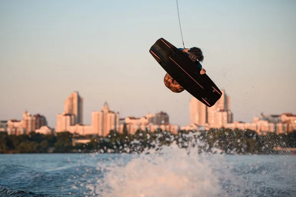 Man wakeboarder gör trick och mästerligt hoppa över stänk våg på wakeboard — Stockfoto