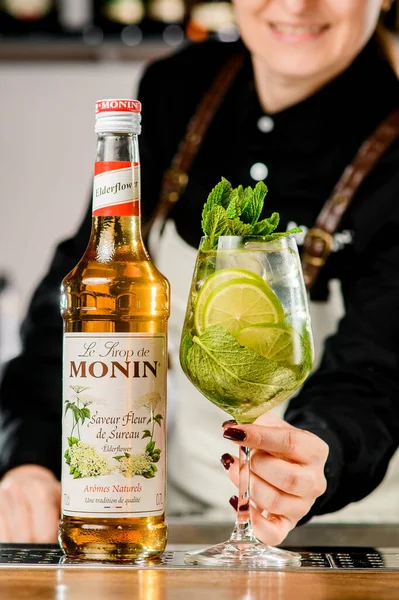 UKRAINE, KYIV - Maart 12, 2021: fles Monin merk siroop en glas heldere frisheid cocktail op bar counter. — Stockfoto