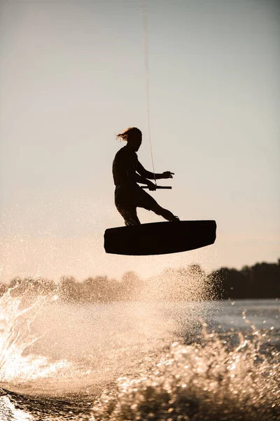 Silhuett av wakeboarder skickligt hoppa höga gör trick i luften — Stockfoto