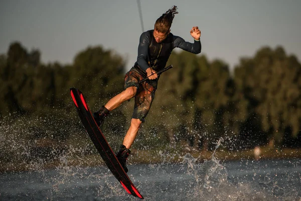 Mâle wakeboarder s'amuser et sauter sur la carte à éclabousser vague de rivière — Photo