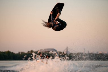 Erkek wakeboardcu aşırı dublörlük yapıyor zıplayarak ve su sıçratan dalgalar üzerinde wakeboard üzerinde takla atıyor
