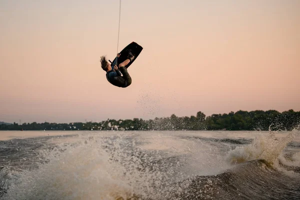 Idrottsman skickligt hoppar och vänder på wakeboard över stänk våg — Stockfoto