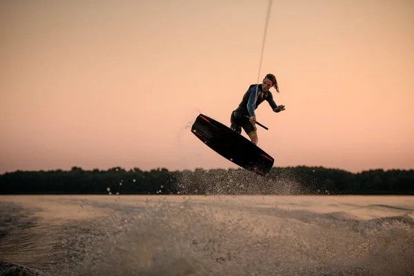 Grande vista da energia wakeboarder masculino enquanto saltando no ar em wakeboard — Fotografia de Stock