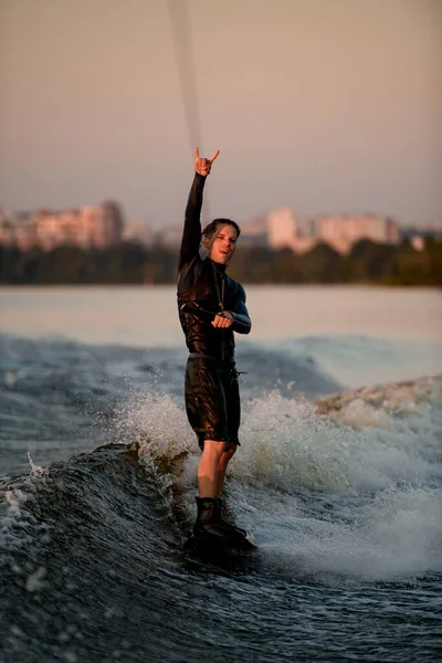 Wakeboarder tiene la corda e cavalca l'onda e mostra il gesto del surfista. — Foto Stock