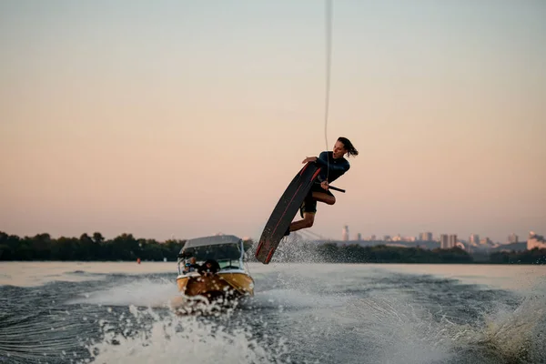 Homme d'énergie s'amuser et sauter sur la vague éclaboussante sur un wakeboard — Photo