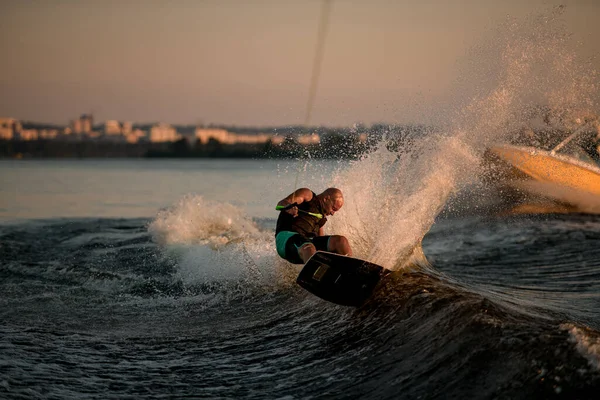Vue dynamique des vagues éclaboussures et wakeboarder mâle essayant de se tenir sur elle — Photo