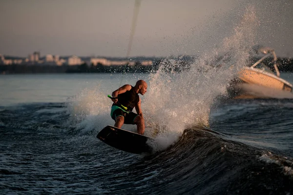 Homme athlétique actif essayant de se tenir debout sur la vague éclaboussante sur un wakeboard — Photo