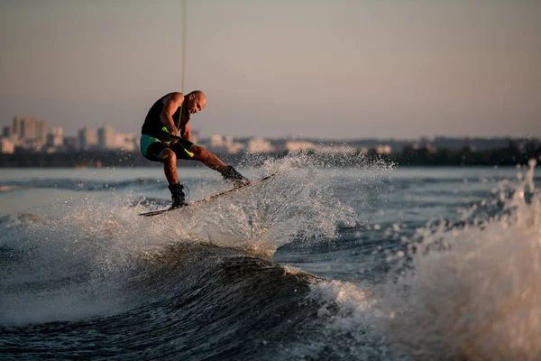 L'uomo forte magistralmente saltando su onda spruzzante su un wakeboard — Foto Stock