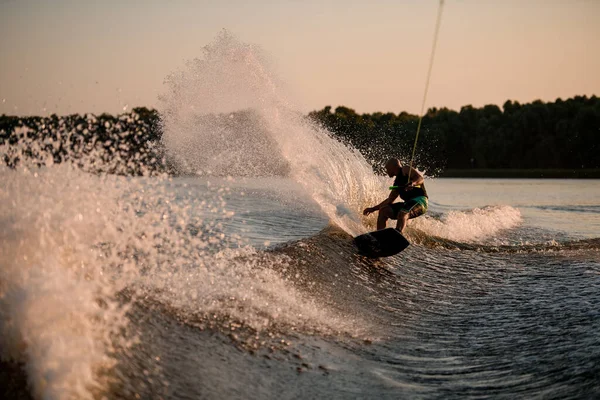 Uomo attivo energicamente bilanciamento su grande onda splasing su wakesboard. — Foto Stock