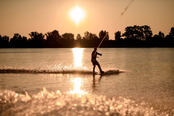 Vue du wakeboarder masculin chevauchant l'eau sur fond de coucher de soleil lumineux — Photo