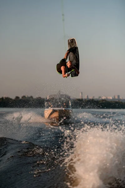 strong man makes dangerous stunts jumping and flips on wakeboard over splashing wave