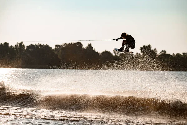 Amazing view of guy holding rope and skillfully jumping high with wakeboard over water — Stock Photo, Image