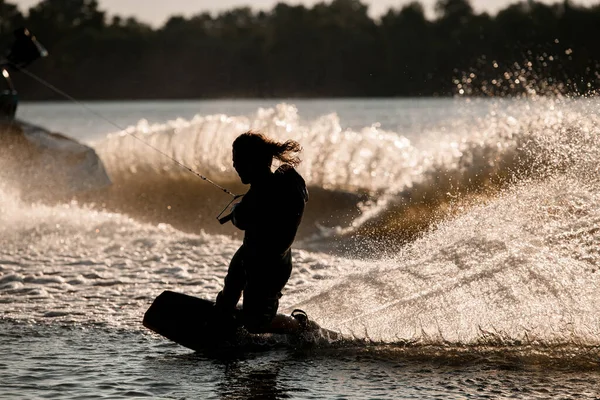 Mojado wakeboarder macho sostiene cuerda tensa y tratando de pararse en salpicaduras ola. —  Fotos de Stock