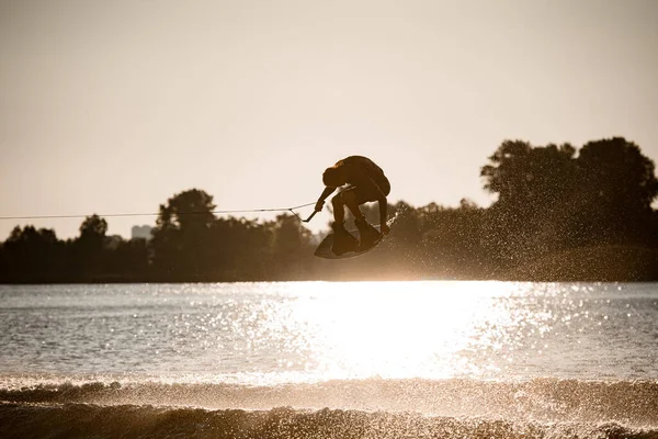 Bella vista di attivo wakeboarder maschile fare acrobazie estreme salto e ribalta sul wakeboard — Foto Stock