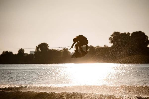 Beautiful view of active male wakeboarder making extreme stunts jumping and flips on wakeboard — Stock Photo, Image