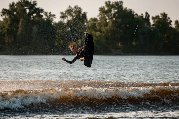 Vy över fallande aktiva manliga wakeboarder med wakeboard över vatten — Stockfoto
